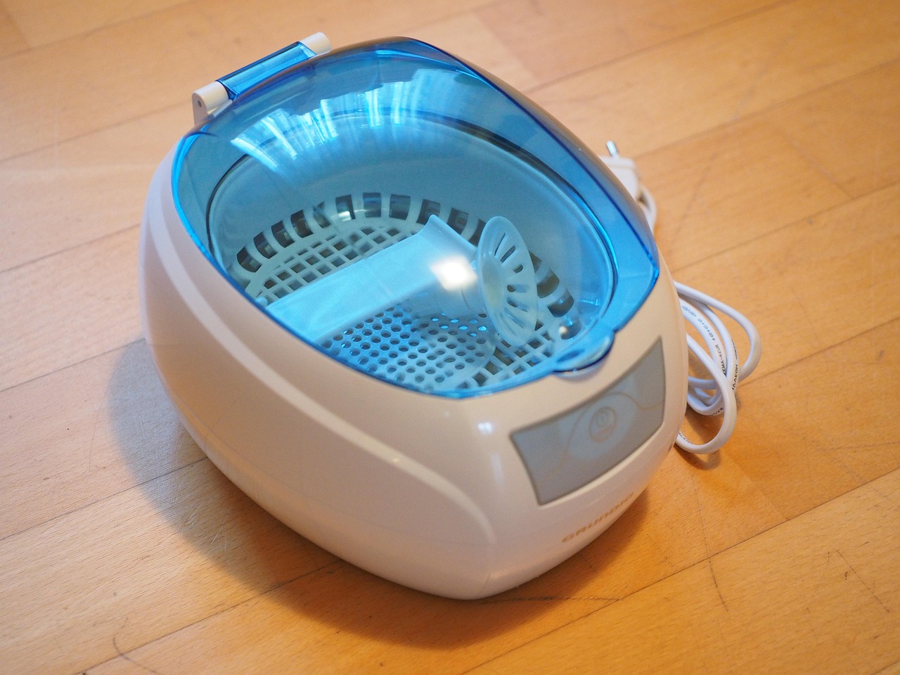 Ultrasonic cleaner gently cleaning a pair of eyeglasses in a water and solution bath