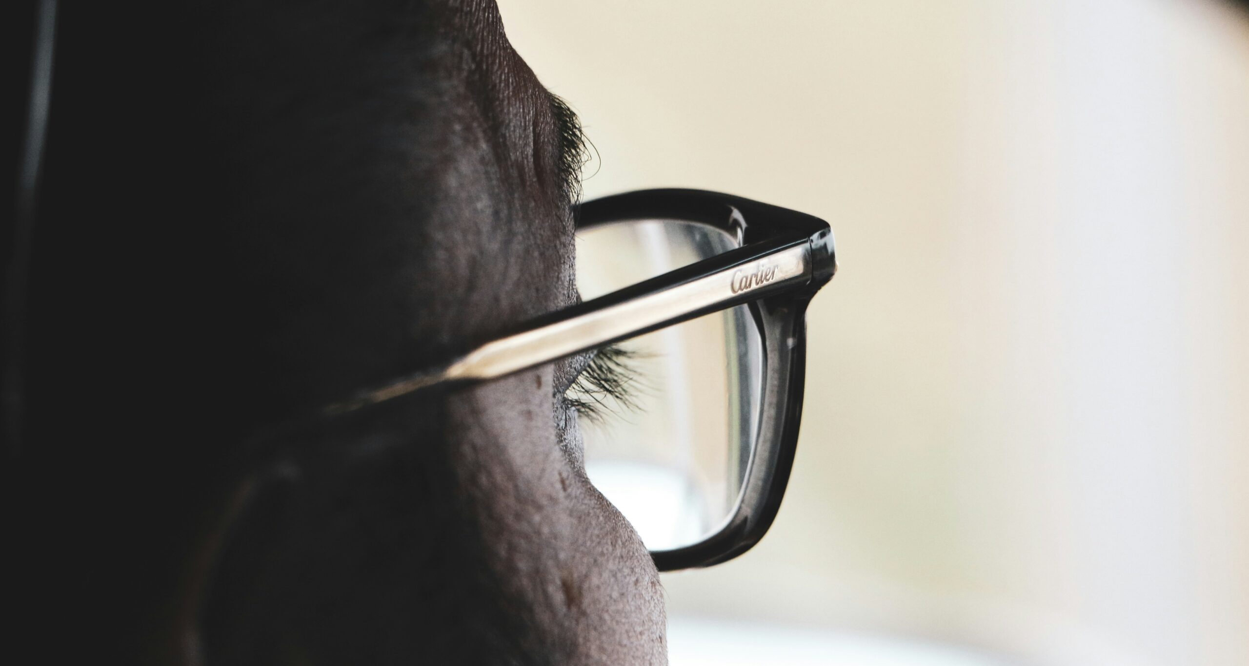 Close-up of eyeglasses with one tinted lens and one transition lens showing light and dark states outdoors